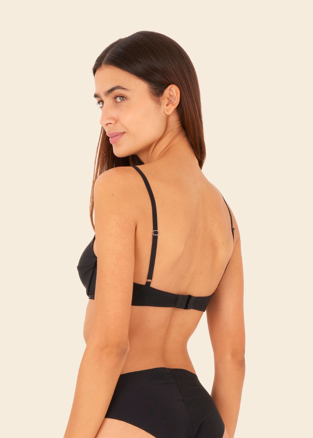 mujer en fondo blanco de espalda usando ropa interior de sosten y tanga en color negro