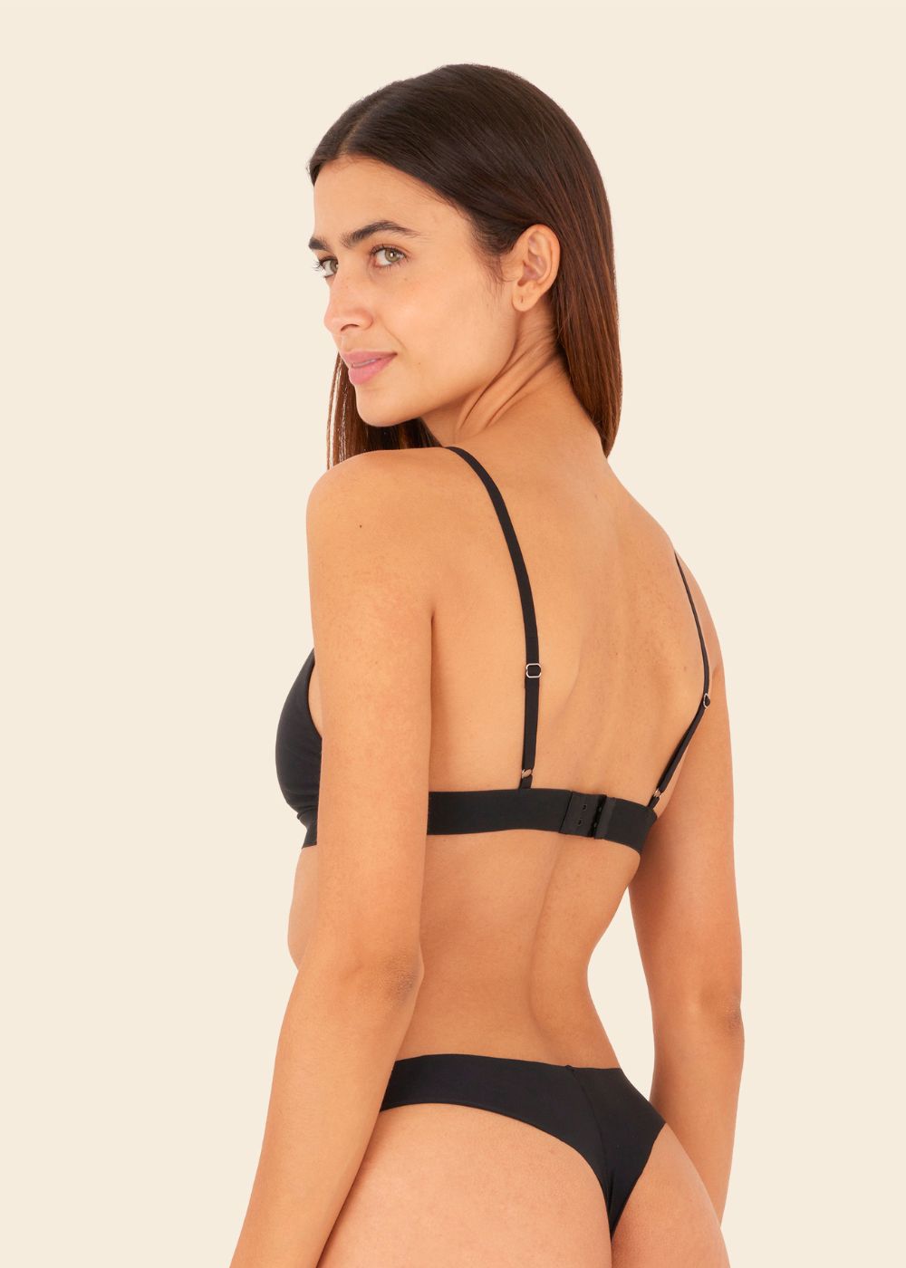 mujer en fondo blanco de espalda usando ropa interior de sosten y tanga en color negro