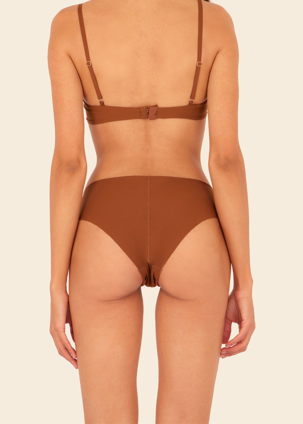 Mujer en fondo blanco de espalda usando ropa interior en color terracota